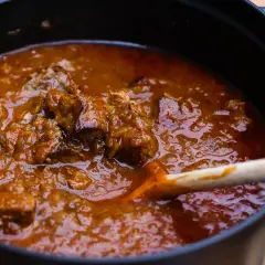 Ein dampfender Topf mit original Wiener Saftgulasch ohne Anbraten. Zarte Fleischstücke in einer würzigen Sauce, bereit zum Servieren.