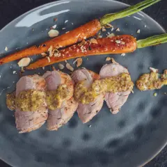 Zarte Scheiben von **schweinefilet grillen** mit Honig-Senf-Sauce und karamellisierten Karotten, bestreut mit Mandelsplittern.
