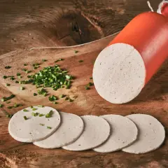 Eine angeschnittene Gelbwurst mit Schnittlauch bestreuten Scheiben auf einem Holzbrett.