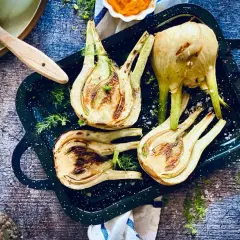 Gegrillter Fenchel in einer Pfanne, mit Kräutern und Öl daneben. Perfekt für ein leichtes Abendessen.