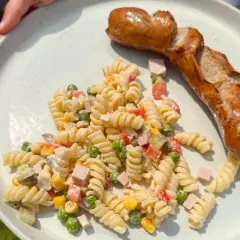 Ein herzhafter Nudelsalat mit Erbsen, Mais und Schinken, dazu eine goldbraune Bratwurst – perfekt, was passt zu Nudelsalat!
