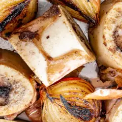 Geröstete Suppenknochen und Zwiebeln, bereit zum Kochen für eine herzhafte Brühe.