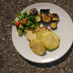 Gegrillte Kohlrabi-Scheiben mit Zucchini und einem kleinen Salat auf einem weißen Teller. Ein leckeres Sommergericht!