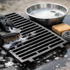 Mit schwarzer Handschuh wird der Grillrost gereinigt. Seife und Bürste helfen, ihn wieder sauber zu bekommen.