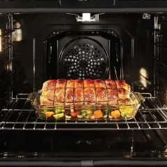 Ein Braten mit Gemüse gart in einem Glasbehälter im Ofen. Perfekt für **niedertemperatur garen** für zartes Fleisch und saftiges Gemüse.