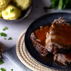 Zartes Fleisch in dunkler Sauce, perfekt für ein klassisches Sauerbraten Rezept. Dazu Klöße und frische Petersilie.