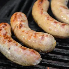 Drei goldbraune Bratwürste brutzeln auf dem Grill. Perfekt für alle, die Bratwurst selber machen wollen.