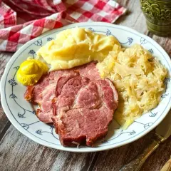 Kassler zubereiten: Saftige Scheiben Kassler mit Kartoffelpüree, Sauerkraut und Senf auf einem Teller. Ein deftiges Gericht, das man gerne isst.