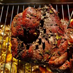 Ein saftiges Rehbraten mit Kräutern und Gewürzen wird auf einem Rost über Gemüse gegrillt.