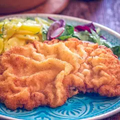Goldbraunes Wiener Schnitzel mit Kartoffelsalat und frischem Grün. Ein perfektes Wiener Schnitzel Rezept für Genießer.