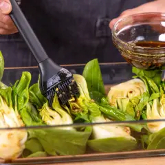 Marinade wird mit einem Pinsel auf halbierten Pak Choi aufgetragen, bereit zum **Pak Choi grillen**.