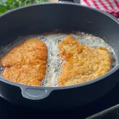 Zwei panierte Schnitzel braten in heißem Öl. Die goldbraune Kruste verspricht ein perfektes Ergebnis.