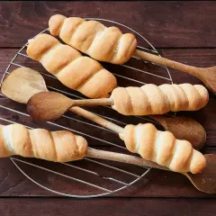 Goldbraunes Stockbrot-Rezept: Teig um Holzstäbchen gewickelt, auf einem Gitter abkühlen. Perfekt für Lagerfeuer!