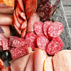 Eine Auswahl an Wurstwaren: Salamischeiben, Kochschinken, Bratwürste und Speck. Die Vielfalt zeigt die **Definition Wurst** in ihrer ganzen Pracht.