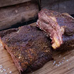 Zwei saftige Brisket-Stücke auf einem Holzbrett, bereit für die Messung der Kerntemperatur. Perfekt gegrillt!