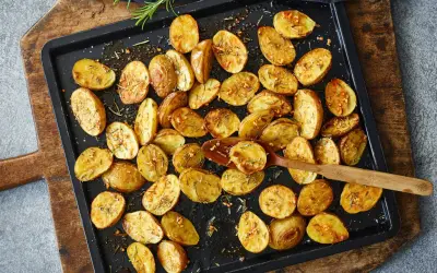 Goldbraune, knusprige Kartoffelspalten mit Rosmarin und Knoblauch, bereit für ein köstliches Ofenkartoffeln Rezept.