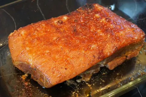 Saftiger Schweinebraten sous vide mit knuspriger Kruste, glänzend und goldbraun, ruht in einer Glasschale.