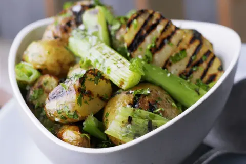 Schmackhaftes Gericht mit gegrillten Kartoffeln und Sellerie, garniert mit frischer Petersilie und grobem Salz. Perfekt für den Sommer.