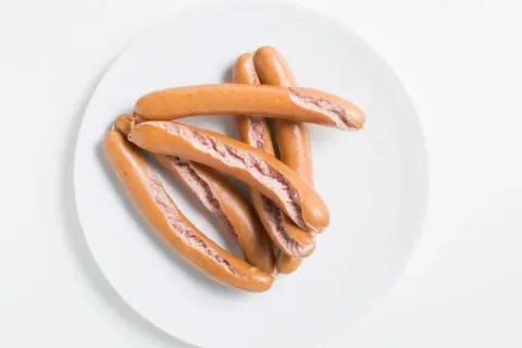 Ein Haufen gekochter Würstchen auf einem Teller. Wie lange wurst kochen?