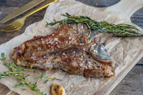 Perfekt gegrilltes Kalbskotelett mit Kräutern und grobem Salz. Die Kerntemperatur ist entscheidend für den perfekten Garpunkt.