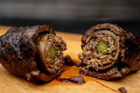 Zwei saftige Rouladen, im Dutch Oven geschmort, zeigen ihre köstliche Füllung aus Gurke und Zwiebeln.