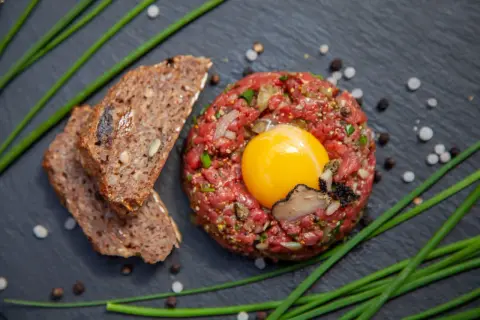 Beef Tatar mit rohem Ei, Trüffel und Brot.