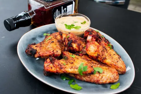 Saftige chicken wings grillen mit Dip und einer Flasche Whiskey. Perfekt für den Sommer!