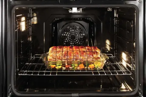 Ein Braten mit Gemüse gart in einem Glasbehälter im Ofen. Perfekt für **niedertemperatur garen** für zartes Fleisch und saftiges Gemüse.