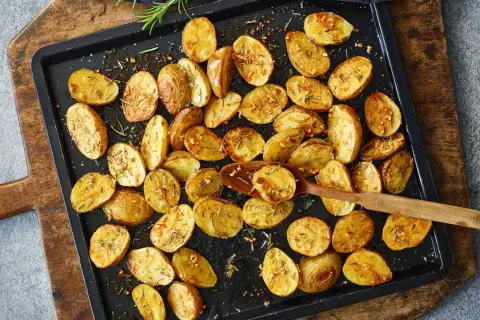 Goldbraune, knusprige Kartoffelspalten mit Rosmarin und Knoblauch, bereit für ein köstliches Ofenkartoffeln Rezept.
