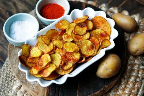 Selbstgemachte Kartoffelchips, goldbraun und knusprig, mit Salz und Paprikapulver. So einfach ist kartoffelchips selber machen!