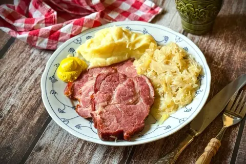 Kassler zubereiten: Saftige Scheiben Kassler mit Kartoffelpüree, Sauerkraut und Senf auf einem Teller. Ein deftiges Gericht, das man gerne isst.