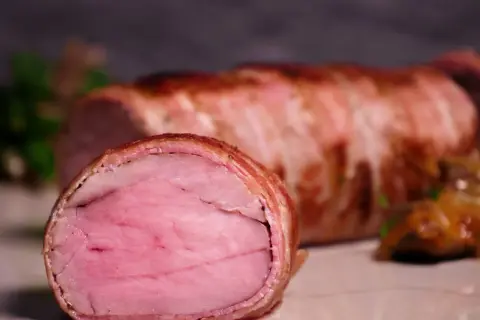 Perfekt gegartes sous-vide schweinefilet, umhüllt von knusprigem Speck. Eine köstliche Beilage, die auf jeder sous-vide schweinefilet tabelle glänzt.