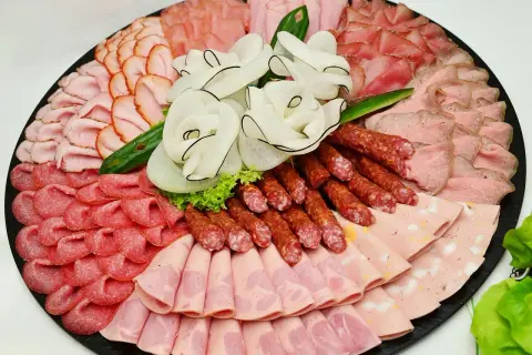 Eine reichhaltige Auswahl an Wurst Sorten, kunstvoll arrangiert auf einer Platte. Verschiedene Schinken-, Salami- und Brühwurst-Varianten laden zum Genuss ein.
