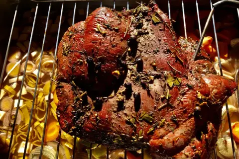 Ein saftiges Rehbraten mit Kräutern und Gewürzen wird auf einem Rost über Gemüse gegrillt.