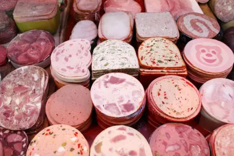 Vielfalt an Wurstsorten mit Bildern: Aufgeschnittene Mortadella, Leberwurst, Salami und mehr.