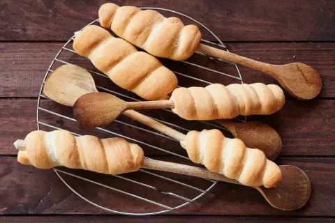 Goldbraunes Stockbrot-Rezept: Teig um Holzstäbchen gewickelt, auf einem Gitter abkühlen. Perfekt für Lagerfeuer!
