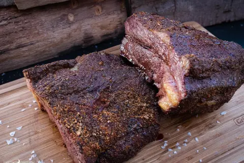 Zwei saftige Brisket-Stücke auf einem Holzbrett, bereit für die Messung der Kerntemperatur. Perfekt gegrillt!