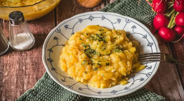 Ein Teller mit Omas Kartoffelsalat, garniert mit Petersilie. Daneben ein Glas mit Salz und Radieschen.