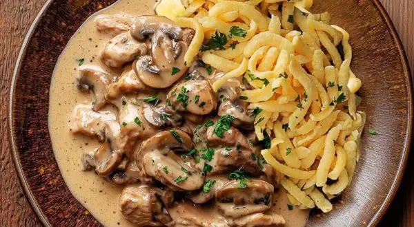 Ein köstliches Schweinegeschnetzeltes Rezept mit cremiger Pilzsoße und Spätzle, garniert mit frischer Petersilie.
