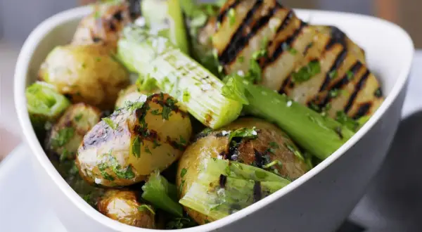 Schmackhaftes Gericht mit gegrillten Kartoffeln und Sellerie, garniert mit frischer Petersilie und grobem Salz. Perfekt für den Sommer.