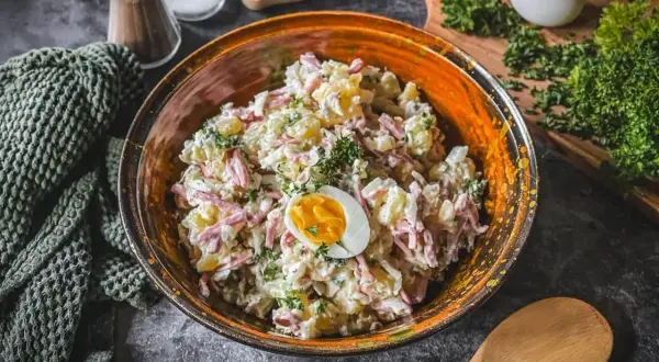 Schüssel mit Kartoffelsalat und Fleischsalat, garniert mit einem halben Ei und Petersilie.