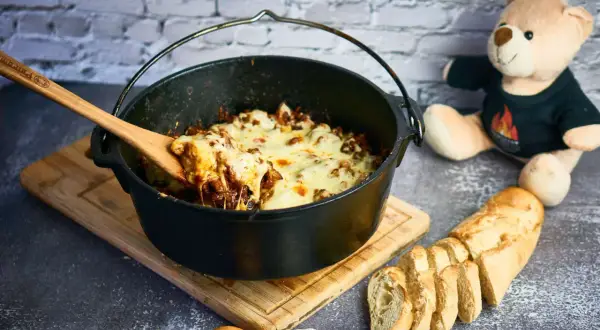 Herzhafter Gyros-Eintopf im Dutch Oven, mit geschmolzenem Käse und Baguette.