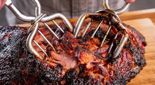 Saftiges Pulled Pork, perfekt für deine Smoker Rezepte. Mit zwei Fleischgabeln wird das zarte Fleisch auseinandergezogen.
