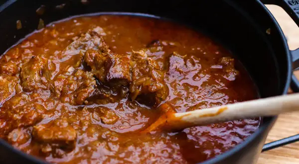 Ein dampfender Topf mit original Wiener Saftgulasch ohne Anbraten. Zarte Fleischstücke in einer würzigen Sauce, bereit zum Servieren.