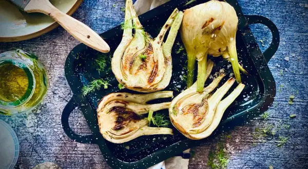 Gegrillter Fenchel in einer Pfanne, mit Kräutern und Öl daneben. Perfekt für ein leichtes Abendessen.