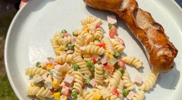Ein herzhafter Nudelsalat mit Erbsen, Mais und Schinken, dazu eine goldbraune Bratwurst – perfekt, was passt zu Nudelsalat!