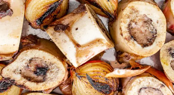 Geröstete Suppenknochen und Zwiebeln, bereit zum Kochen für eine herzhafte Brühe.