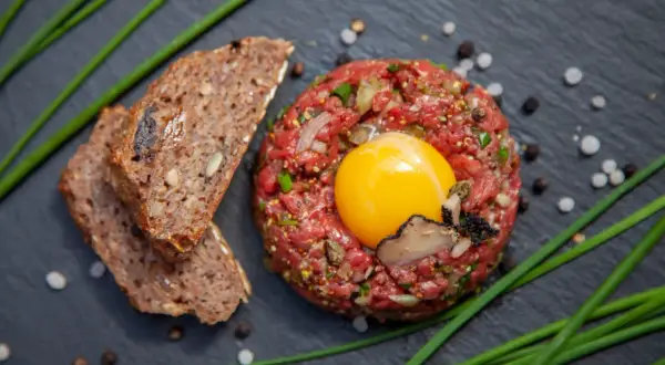 Beef Tatar mit rohem Ei, Trüffel und Brot.