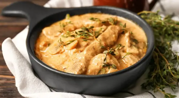 Cremiges Boeuf Stroganoff Rezept mit zarten Fleischstreifen und Pilzen, garniert mit frischem Thymian.