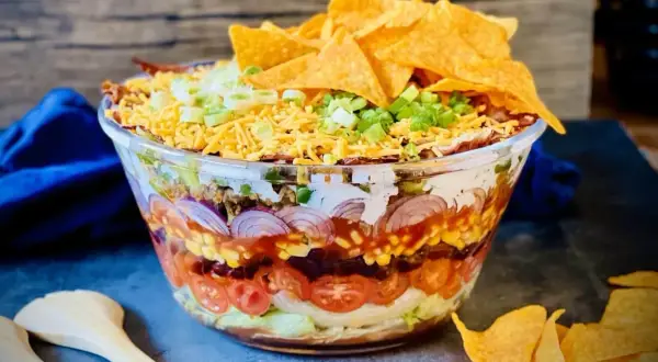 Schichtsalat mit Hackfleisch, Bohnen, Mais, Tomaten, Zwiebeln, Käse und Tortilla-Chips. Perfekt für Taco-Salat Rezepte!